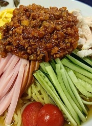 介護施設の食事。ミンチ肉炒め、ハム、きゅうり、トマト、卵焼きなど栄養バランスの取れた一皿。
